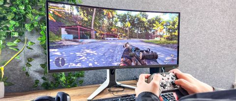 Alienware 34 Curved QD-OLED Gaming Monitor on a desk showing a game being played