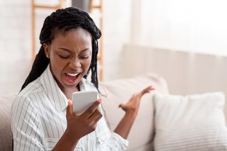 Young woman shouting at her smartphone.