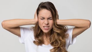 A woman holding her hands to her ears to block out the noise