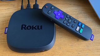 The Roku Ultra (one of the best Roku devices) and its remote, on a wooden surface
