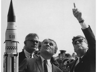 Dr. Wernher von Braun (center) describes the Saturn Launch System to President John F. Kennedy (right, pointing). NASA Deputy Administrator Robert Seamans stands to the left of von Braun.