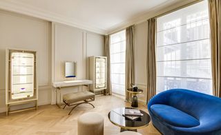 Make-up table with stool, two illuminated cabinets displaying beauty products and a blue couch with a coffee table