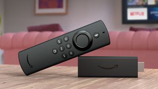 Amazon Fire TV Stick Lite with its remote propped up on its corner in front of a sofa and TV showing the Netflix app