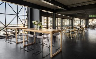 Interior view of the restaurant showcasing the hard steel design with high tables and high chairs, and dressed dining tables with chairs