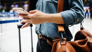 A close-up of a woman in an airport using a smartphone