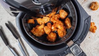 An air fryer basket containing breaded chicken