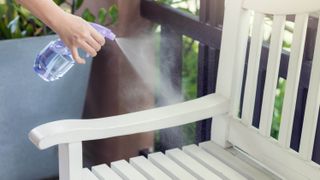 A bottle spraying water onto a wooden chair