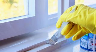 Person painting a windowsill with a high gloss white paint