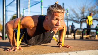 a photo of a man doing push-ups with resistance bands