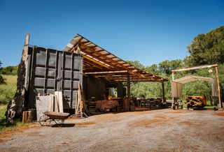 Ido Yoshimoto's workshop in Inverness, California, photographed under a blue sky and with wooden elements from his production