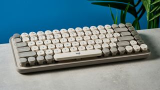 A photo of the Logitech Pop Keys keyboard on a stone surface against a blue background