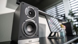 Elac Debut ConneX DCB41 speaker next to computer and TV in a living room setting