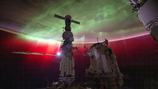 the earth with a large aurora shining on it. in front is the international space station in shadow