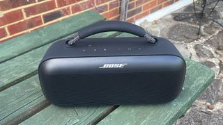 Bose SoundLink Max wireless speaker on green wooden garden bench