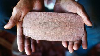 A person tolds a wooden tablet of Rongorongo script from Rapa Nui.