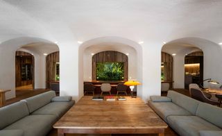 A sitting area with large tables, grey sofa's and a plant feature wall.