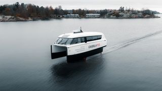 A small, compact white boat in the centre of a channel looks as though it is hovering over the water