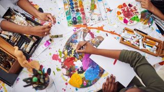 people painting on top of a table withy easels and paper from shutterstock