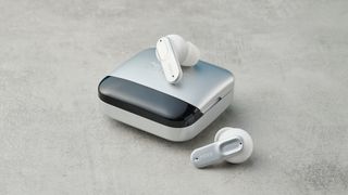 mixx streambuds ultra mini case rests upon a table, with one earbud inside the case and one earbud on the table nearby