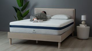 Saatva vs Helix mattress: the Helix Midnight mattress on a wooden bedframe, against a dark wall