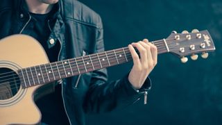 A guitar player fretting a chord