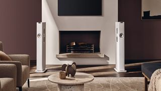A pair of white KEF LS60 Wireless floorstanding speakers either side of a fireplace.