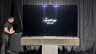 dynaudio Symphony Opus One soundbar on a stand in front of a TV