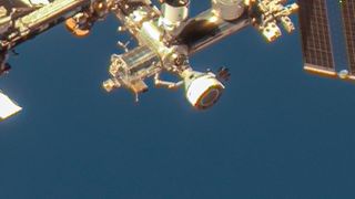 a cone-shaped spacecraft attached to a sprawling metal space station