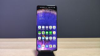 En Oppo Find X5 står på ett träfärgad bord med hemskärmen aktiv.