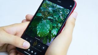 A person holding an iPhone, editing an image, representing an article about how to edit photos on iPhone