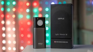 The Opple Light Master 4 next to its box with Christmas lights in the background