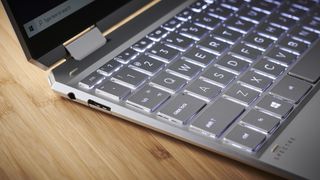 HP Spectre x360 on a wooden desk showing off its ports and part of its keyboard