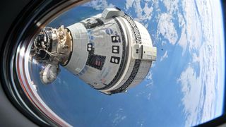 A white and black Boeing Starliner space capsule is seen docked at the International Space Station through a station window with the Earth below.