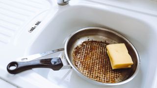 A pan with burnt-on food in a kitchen sink