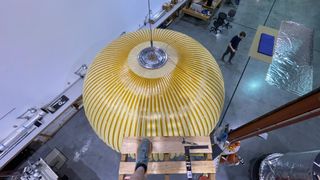 top-down view of a yellow spherical test space habitat inside a white-walled building.