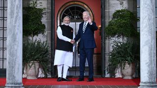 two men shake hands in front of a large building with many columns