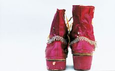 Rear view of two pink boot shows with slightly worn sole. The boots have a decorative attachment around them. 