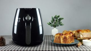 An air fryer sitting on a table next to some bread and oil