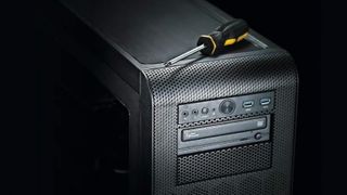 A tower PC against a black background with a screwdriver on top