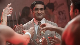 Somen "Steve" Banerjee (Kumail Nanjiani) smiling at the center of a toast in Welcome to Chippendales