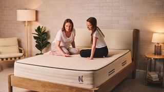 Two women sit on the Nolah Natural 11 Mattress