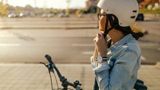 Image of woman putting on helmet before cycling