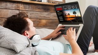 Man on a sofa streaming TV shows on a laptop via a VPN