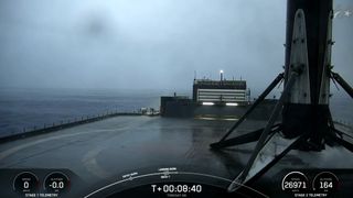 a rocket rests on the deck of a ship at sea, under gray, cloudy skies.