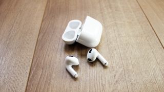 Apple Airpods 3 ved siden av deres trådløse ladeetui