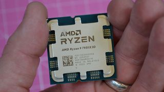 An AMD Ryzen 9 7950X3D held between a man&#039;s fingers