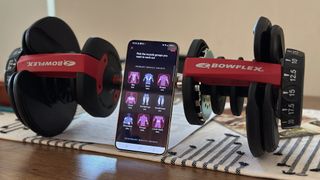 The Galaxy S22+ sitting in front of a Bowflex dumbbell, showing the FitBod Android app.