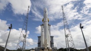 a white rocket on a launch pad beneath cloudy skies