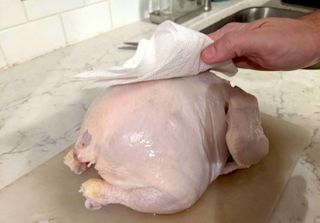 patting chicken dry on countertop