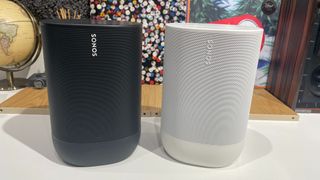 A black Sonos Move and a white Sonos Move 2 side by side on a desktop